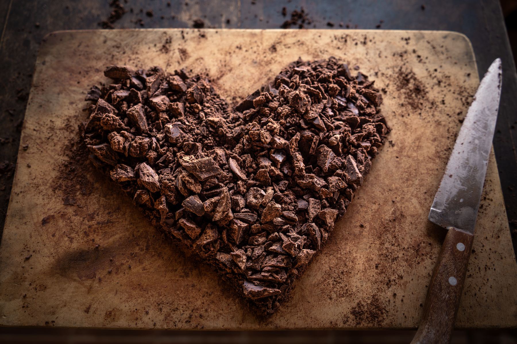 Crushed ceremonial cacao arranged into a heart shape on a wooden board