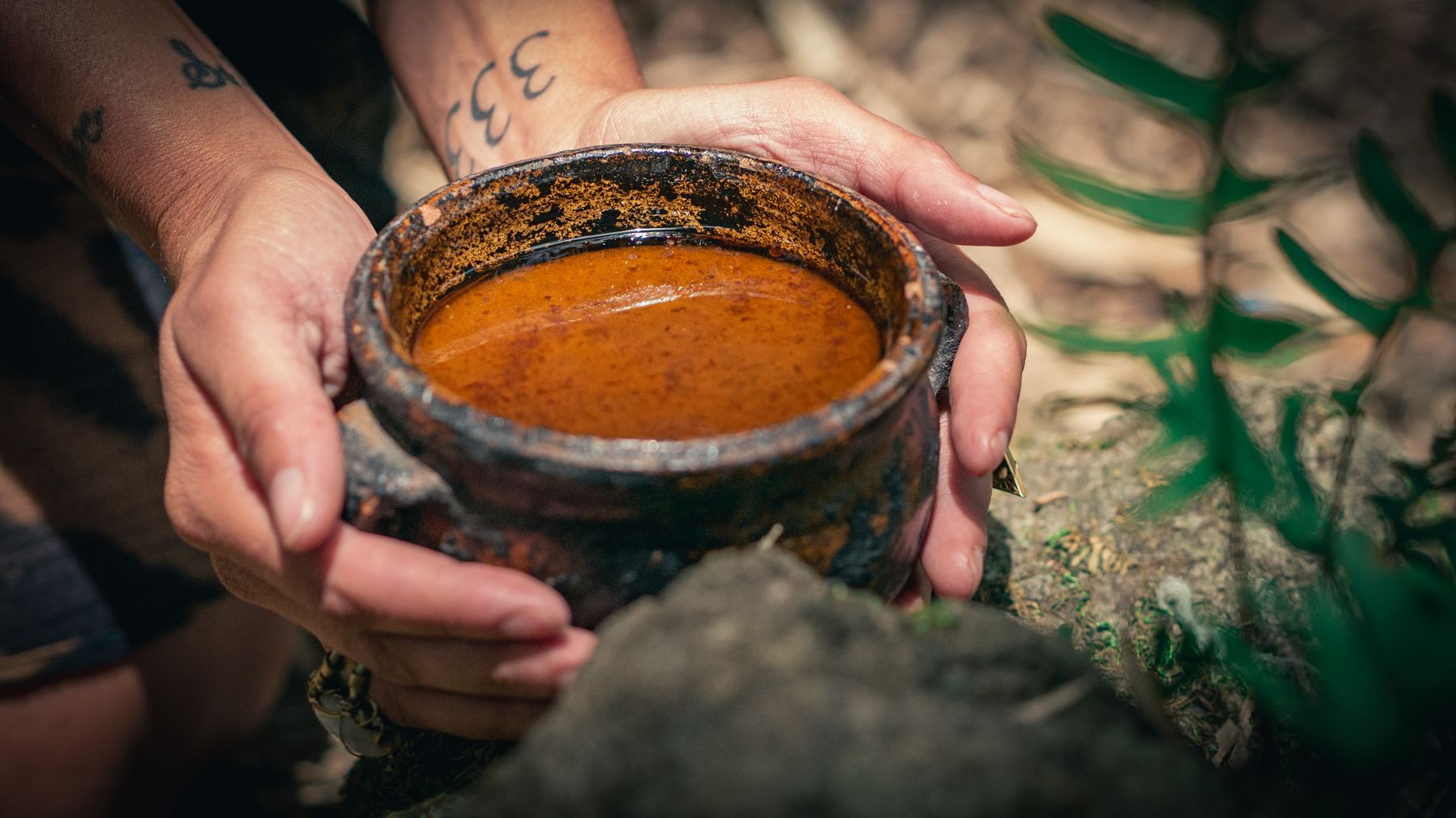 Hands holding a clay bowl of freshly prepared ceremonial cacao