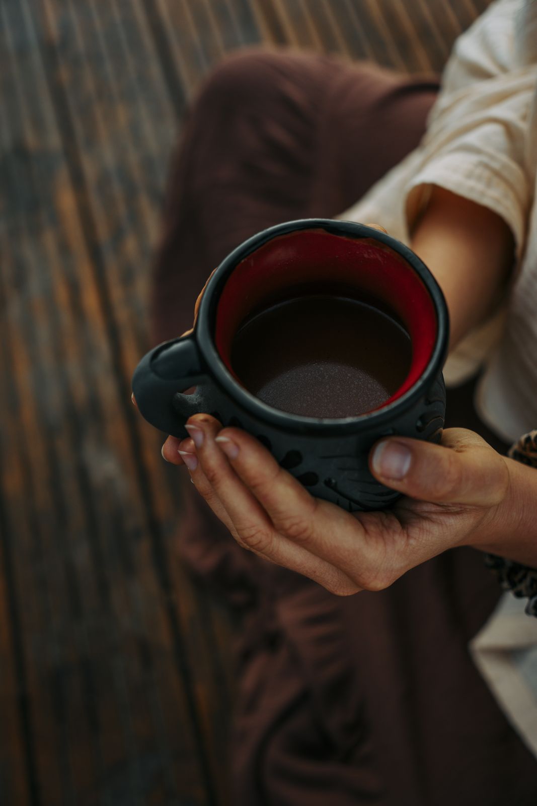 A woman holding a handmade clay cup of ceremonial cacao
