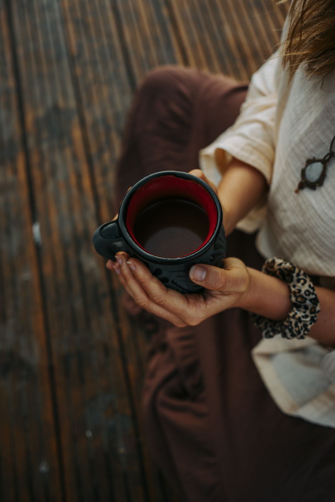A woman holding a handmade clay cup of ceremonial cacao