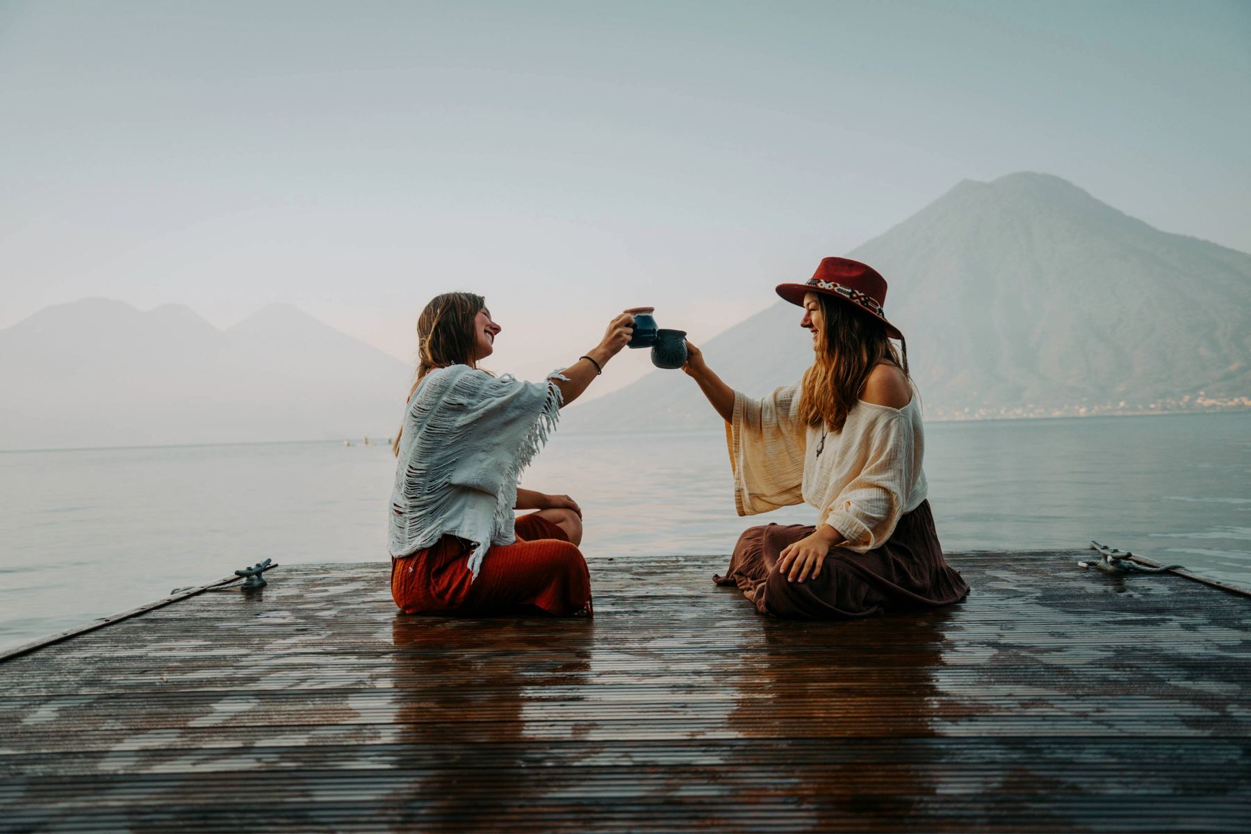 Anya and Laura, the founders of Volcano Spirit Cacao, sharing a toast on a dock at Lake Atitlán